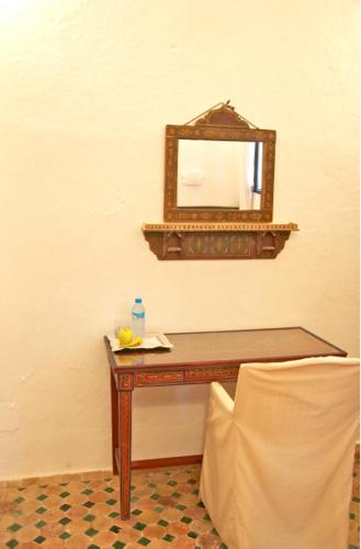 a table with a mirror and a chair in a room at Dar Rass El Maa in Chefchaouene
