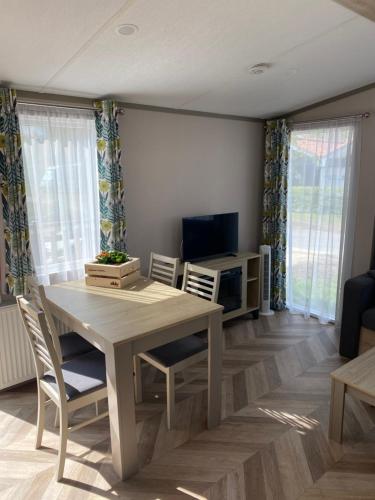 a dining room with a table and chairs and a television at Chalet 4 personen HZ 18 in Lauwersoog