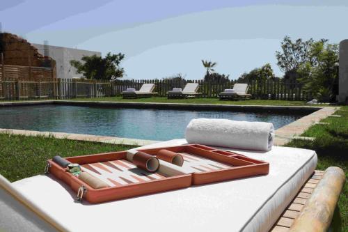 a tray on a bed next to a swimming pool at Quinta Baltazar Casa particular in Vila Nova De Cacela