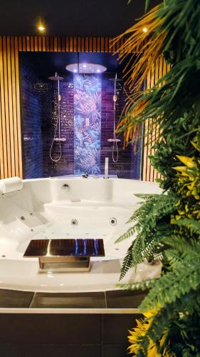 a white bath tub in a room with plants at Toi et moi Love room avec Hammam, Sauna, Balnéothérapie ensemble privatisés in Le Coudray