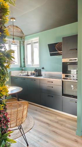 - une cuisine avec des murs bleus, une table et un évier dans l'établissement Toi et moi Love room avec Hammam, Sauna, Balnéothérapie ensemble privatisés, à Le Coudray