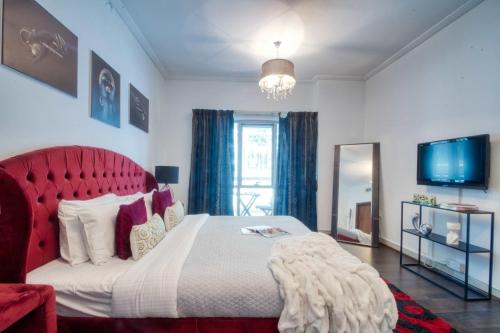 a bedroom with a large bed with a red headboard at The Smart Concierge - Delphine in Dubai