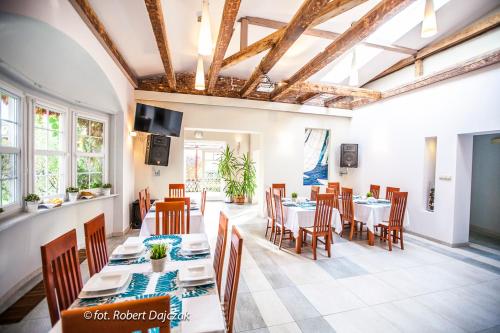 a dining room with white tables and chairs and windows at OŚRODEK KOLONIJNO WCZASOWY MEWA - przy plaży z basenem z podgrzewaną wodą i mini SPA in Niechorze
