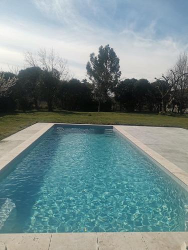 une piscine avec de l'eau bleue dans une cour dans l'établissement La Canolière - Chambre d'hôtes Augustin, à Sauveterre-Saint-Denis