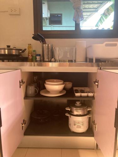 a kitchen with a shelf with bowls and other items at Seasalt house 3 in Ban Madua Wan