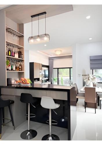 a kitchen with a large island with bar stools at เพชรกล้าพูลวิลล่า in Ban Noi
