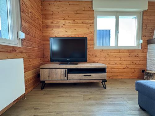 - un salon avec une télévision à écran plat sur un mur en bois dans l'établissement Chambre Hiver, à Anould