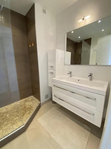 une salle de bain blanche avec un lavabo et un miroir dans l'établissement GRAND PAVOIS Magnifique appartement climatisé, vue mer, piscine, à Cavalaire-sur-Mer