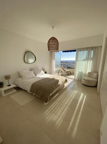 une chambre blanche avec un lit et une grande fenêtre dans l'établissement GRAND PAVOIS Magnifique appartement climatisé, vue mer, piscine, à Cavalaire-sur-Mer