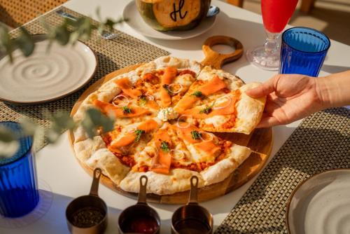 a person is holding a pizza on a table at Andaman Beach Hotel Phuket - Handwritten Collection in Patong Beach
