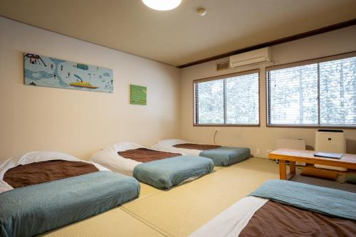 a room with three beds and a desk and windows at LAMP Nojiriko The Sauna by the Lake in Shinano