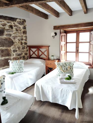 a bedroom with two beds and a stone wall at El Limonero in Arenas de Iguña