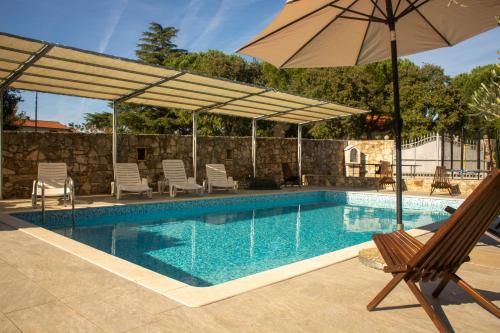 a swimming pool with an umbrella and a chair at Apartments with Pool Villa Fjord in Kanfanar