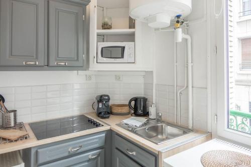 une cuisine avec un évier et un micro-ondes dans l'établissement Le Cosy Studio Hyper-centre, à Orléans
