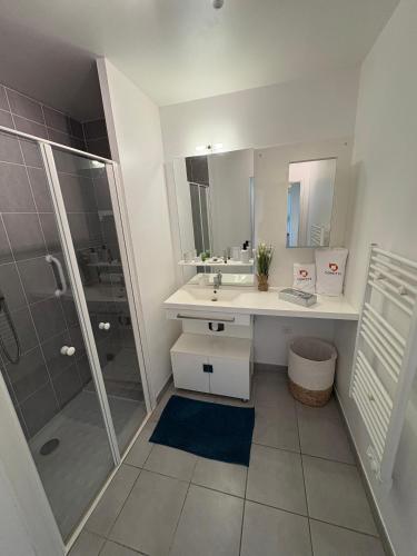 une salle de bain blanche avec un lavabo et une douche dans l'établissement Domitys Le Côteau d'Argent, à Saint-Doulchard