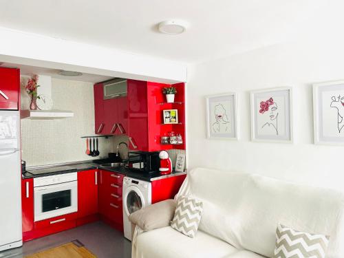 a kitchen with red cabinets and a white couch at Céntrico y acogedor en Burgos in Burgos
