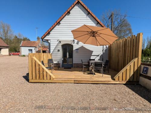 a deck with an umbrella and chairs and a house at Gite Valloires piscine chauffée in Rue