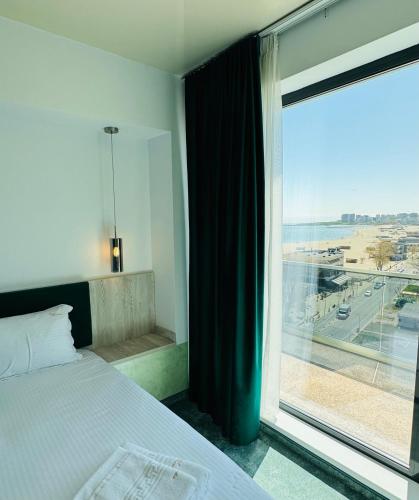 a bedroom with a bed and a large window at Hotel Alexandra in Mamaia