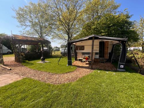 a camper in a yard with a gazebo at Camping Wijndomein Erve Wisselink in Eibergen