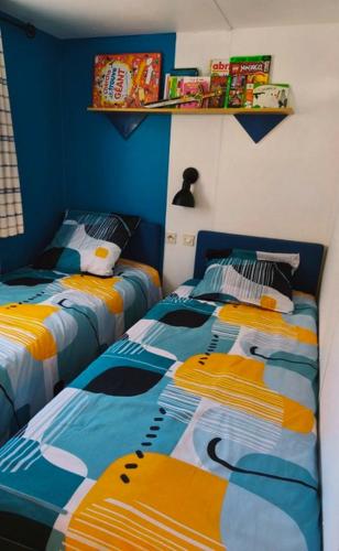 - 2 lits dans une chambre de couleur bleue et jaune dans l'établissement Mobil-home au camping 5 étoiles L'Oasis Village - Montana Parc, à Puget-sur Argens