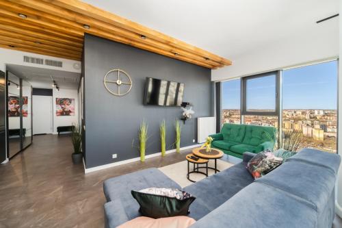 a living room with a blue couch and large windows at Hanza Tower Apartment no 2210 - 22nd floor, swimming pool, jacuzzi, panorama view in Szczecin