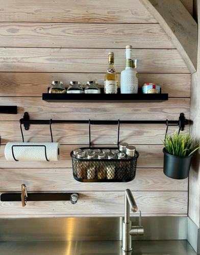 a kitchen counter with a sink and a shelf with bottles at La Perle du Fierain in Wegnez