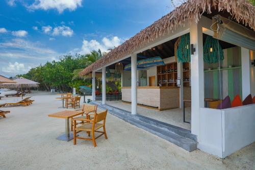a restaurant on the beach with tables and chairs at Cinnamon Dhonveli Maldives in North Male Atoll