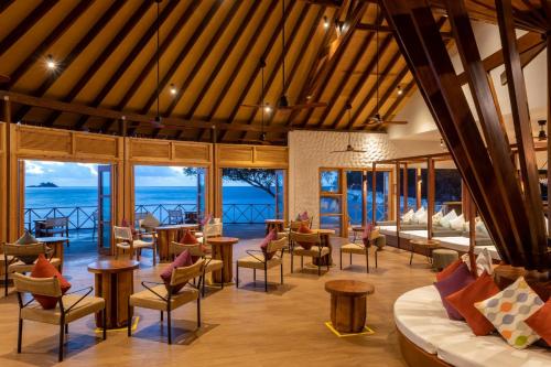 a hotel lobby with tables and chairs and the ocean at Cinnamon Dhonveli Maldives in North Male Atoll
