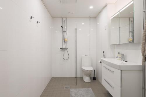 a white bathroom with a toilet and a sink at Fredika, modern 1br,Tripla Pasila prime location, gym, parking, train station near in Helsinki