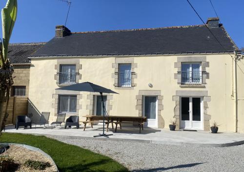 a house with a bench and an umbrella in front of it at L'instant d'un souvenir in Taupont