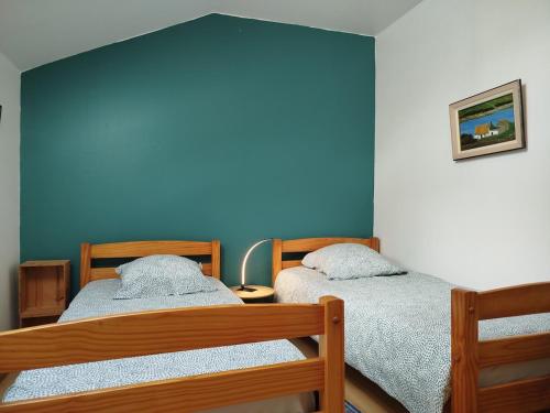 two beds in a room with a blue wall at La maison du Trieux in Lézardrieux