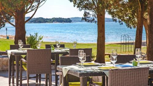 a table with chairs and wine glasses on the beach at Mobile Home Kamp Pineta - IB Studio in Fažana