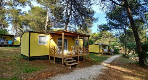 a yellow tiny house in the woods at Mobile Home Kamp Pineta - IB Studio in Fažana