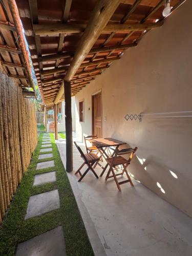 un patio con 2 sillas y una mesa de madera en Vila Kairós, en Caraíva