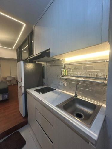 a kitchen with a sink and a refrigerator at Pakuwon Orchard Tanglin Surabaya in Surabaya