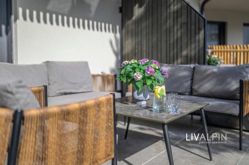 a living room with a couch and a table with flowers at LIVALPIN Comfort in Garmisch-Partenkirchen