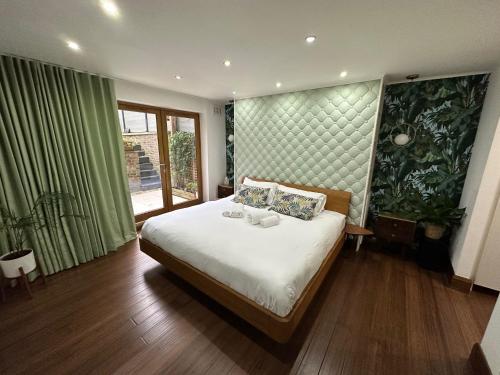 a bedroom with a bed and a large window at Unique Luxury Home in the heart of London. Air conditioned with private garden in London