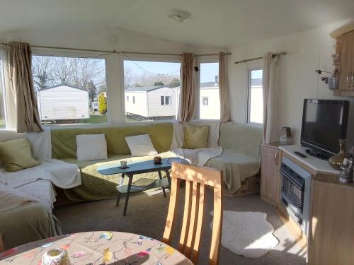 a living room with a green couch and a tv at Private caravan situated at Parkdean Holiday Resort St Margaret's at Cliffe number 18 in St Margarets at Cliff