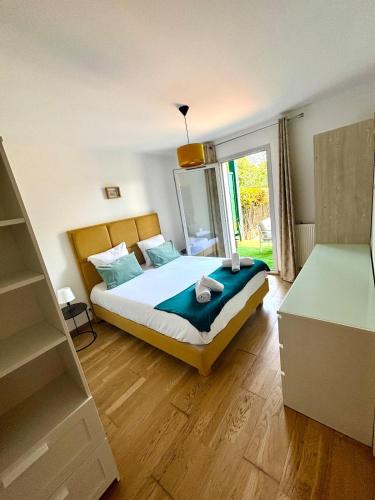 a bedroom with a bed and a large window at Joli T2 avec jardin proche du château d'Arcangues in Arcangues