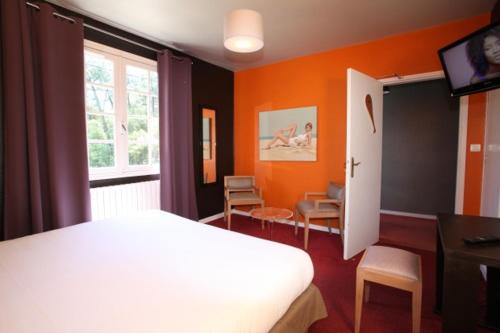 - une chambre avec des murs orange, un lit et une télévision dans l'établissement Paloma, à Hossegor