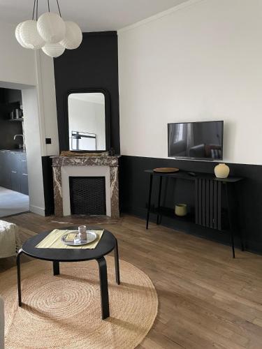 un salon avec une table et une cheminée dans l'établissement Comfort & Design Apartment in Orléans, à Orléans