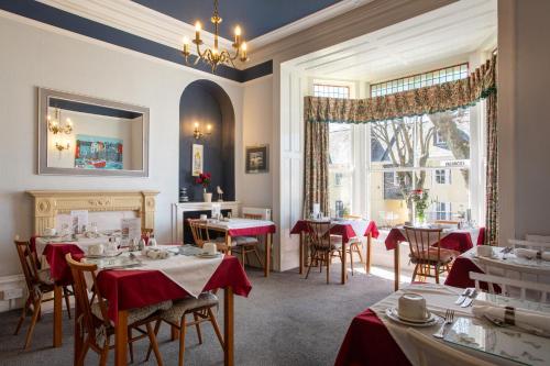 a restaurant with tables and chairs and a fireplace at Dunedin Guest House in Penzance