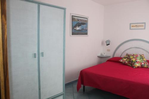 a bedroom with a red bed and a glass closet at Le Case dei pescatori - Sirena in Arcipelago Ponziano