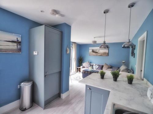 ein Wohnzimmer mit blauen Wänden und einer Küche in der Unterkunft Loughview Cottage in Bangor