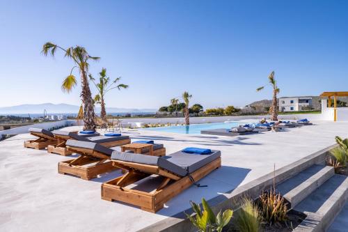 a resort with a pool and lounge chairs and palm trees at Kastraki Riviera in Kastraki Naxou