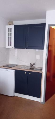 une cuisine avec des armoires bleues et un évier dans l'établissement Studio Sainte Marie De Campan, à Sainte-Marie-de-Campan