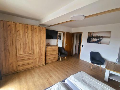 a living room with wooden cabinets and two chairs at Pension Landhaus Koller - Adults only in Bodenmais