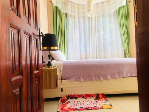 a bedroom with two beds and a window at Elanza Suites Entebbe in Kisubi