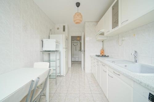 une cuisine blanche avec des armoires blanches et un évier dans l'établissement appartement saint ouen sur Seine, à Saint-Ouen