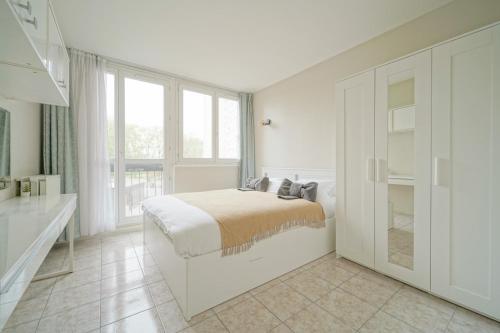 une chambre blanche avec un lit et une grande fenêtre dans l'établissement appartement saint ouen sur Seine, à Saint-Ouen